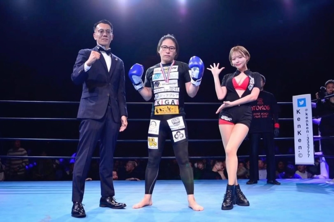 Yoshikawa with a medal and gloves raised after winning the Otokogi tournament